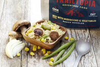 Adventure food package with prepared ramen noodles in bowl alongside fresh vegetables and spoon