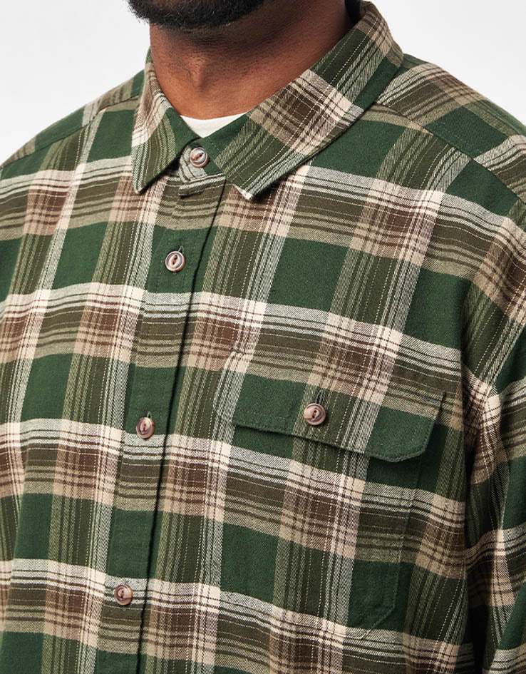Men's plaid flannel shirt in green and brown tartan, chest pocket detail close-up