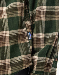 Close-up detail of a plaid flannel shirt pocket with small brand label, green and brown tartan pattern