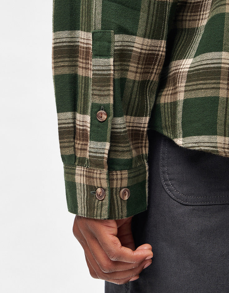 Close-up of plaid flannel shirt sleeve cuff with brown buttons, showing detail on model