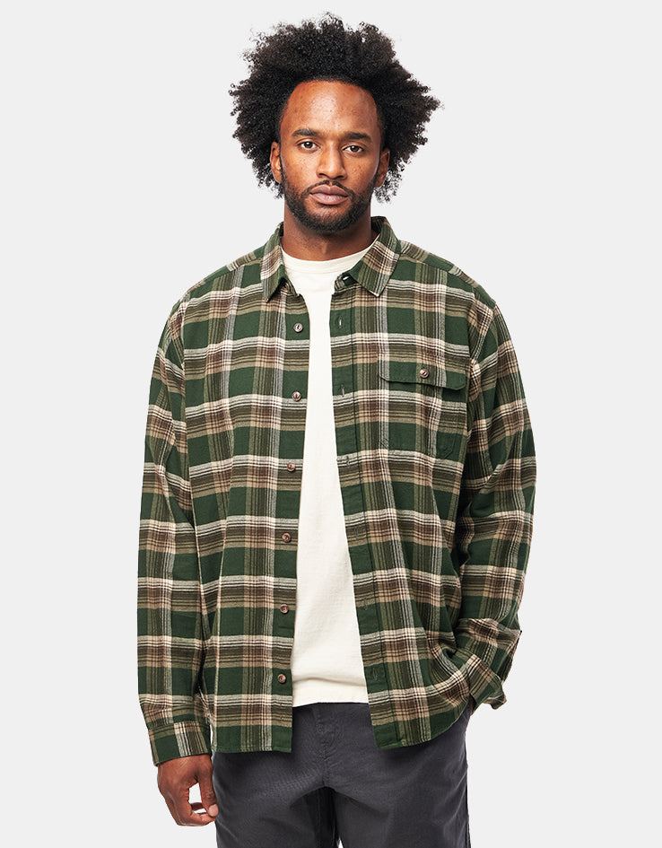 Men's long-sleeve plaid flannel shirt in green tartan, worn open over white tee, front view