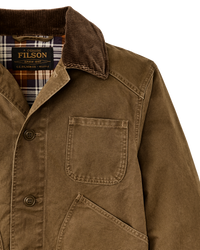Close-up detail of waxed canvas jacket with corduroy collar, chest pocket, and plaid lining