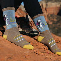 Crew hiking socks with husky dog pattern on blue band, yellow toe and heel, worn on red rock