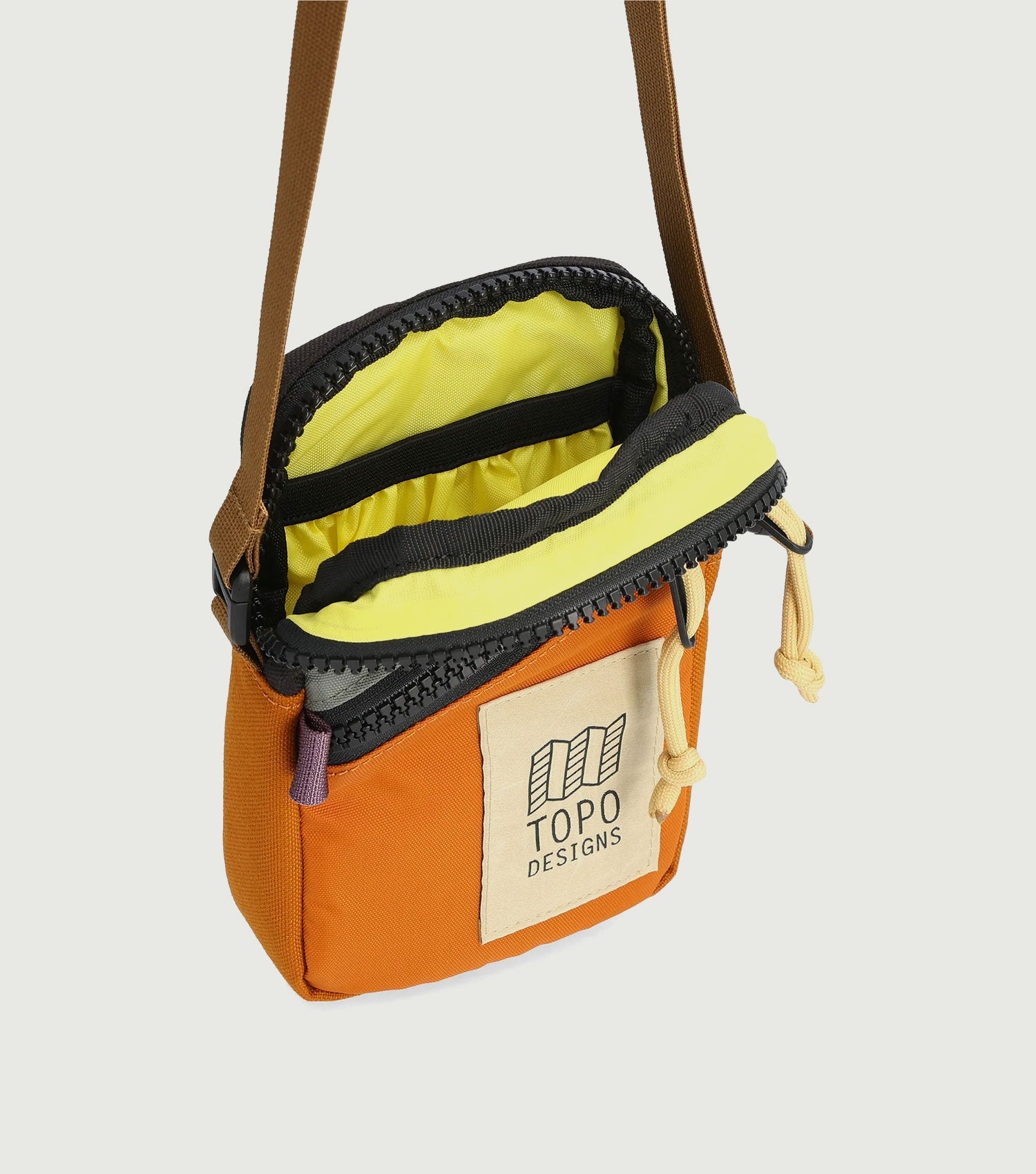 Small crossbody bag with orange and cream panels, yellow interior, brown shoulder strap