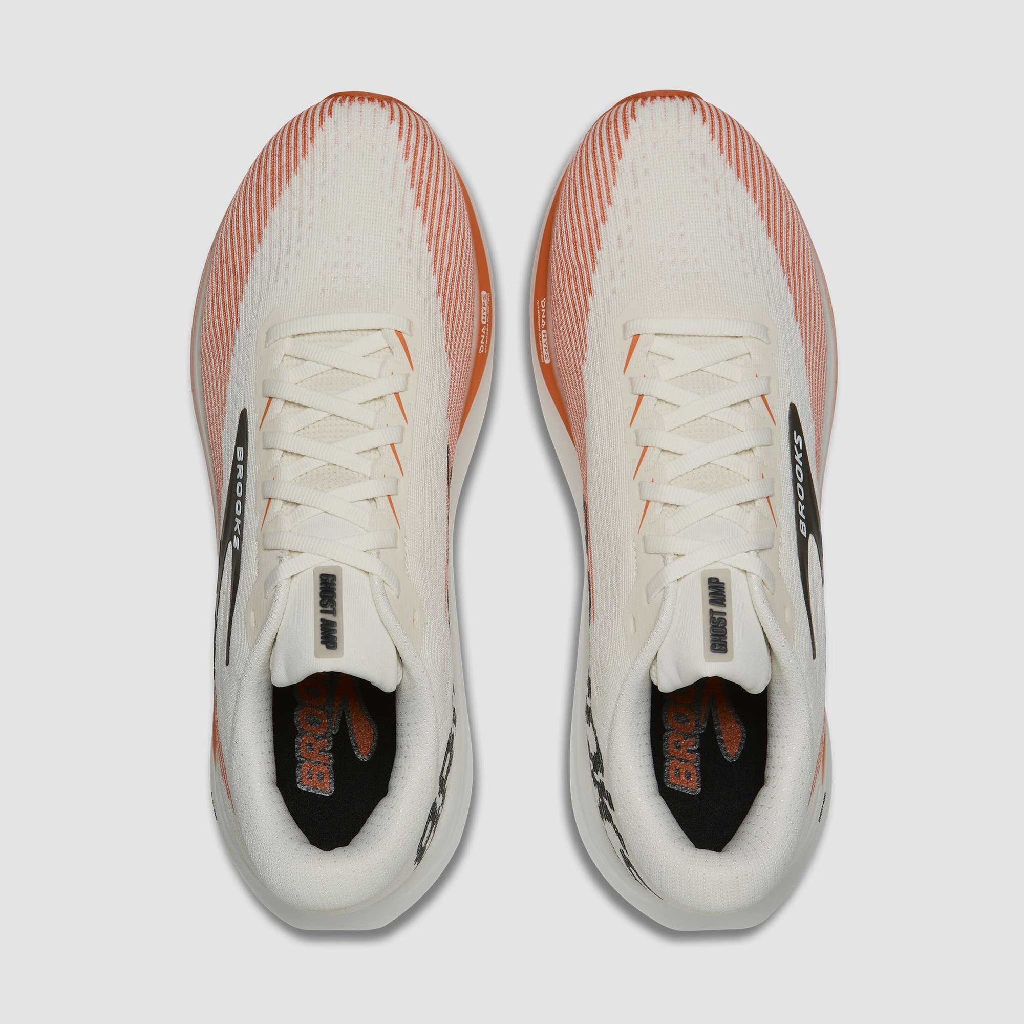 Top-down view of a pair of lace-up running shoes with cream upper and orange accents