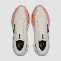 Top-down view of a pair of lace-up running shoes with cream upper and orange accents
