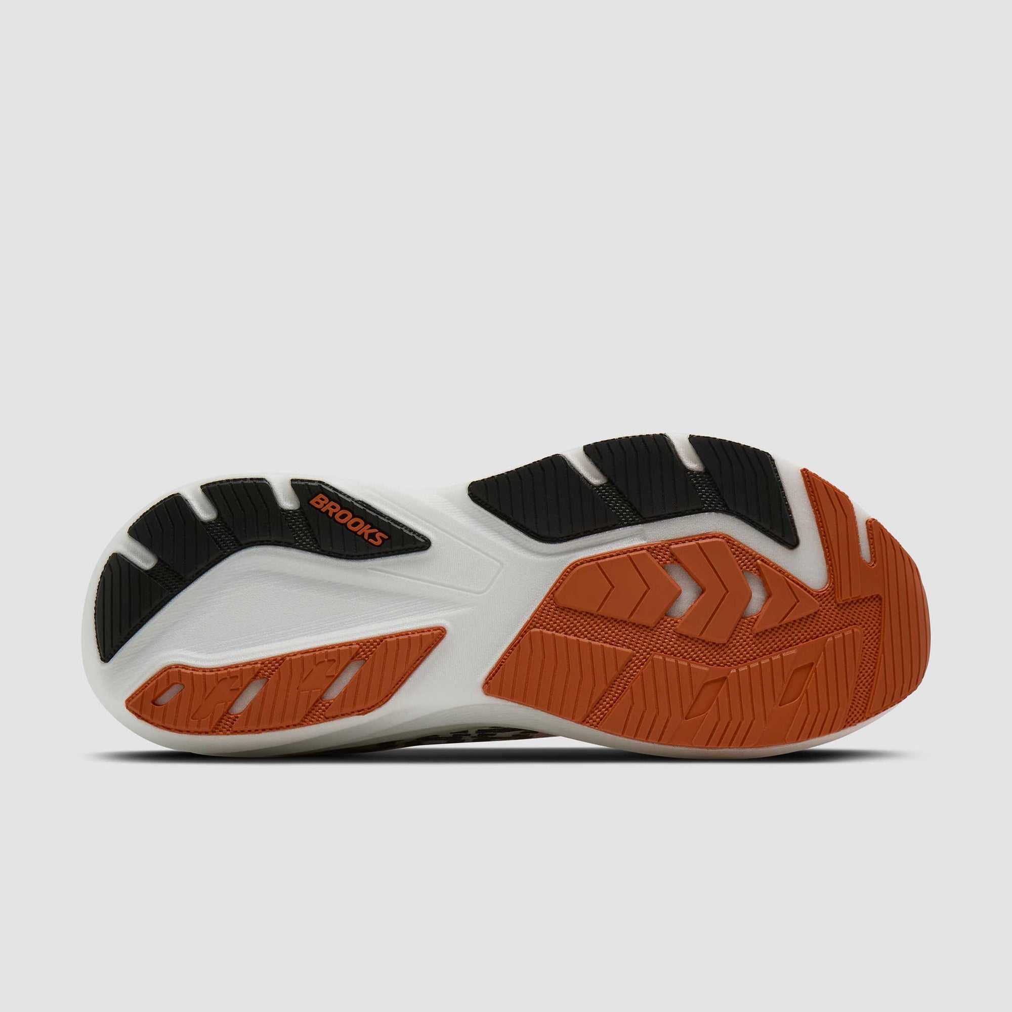 Running shoe bottom view showing white midsole with orange and black rubber outsole tread pattern
