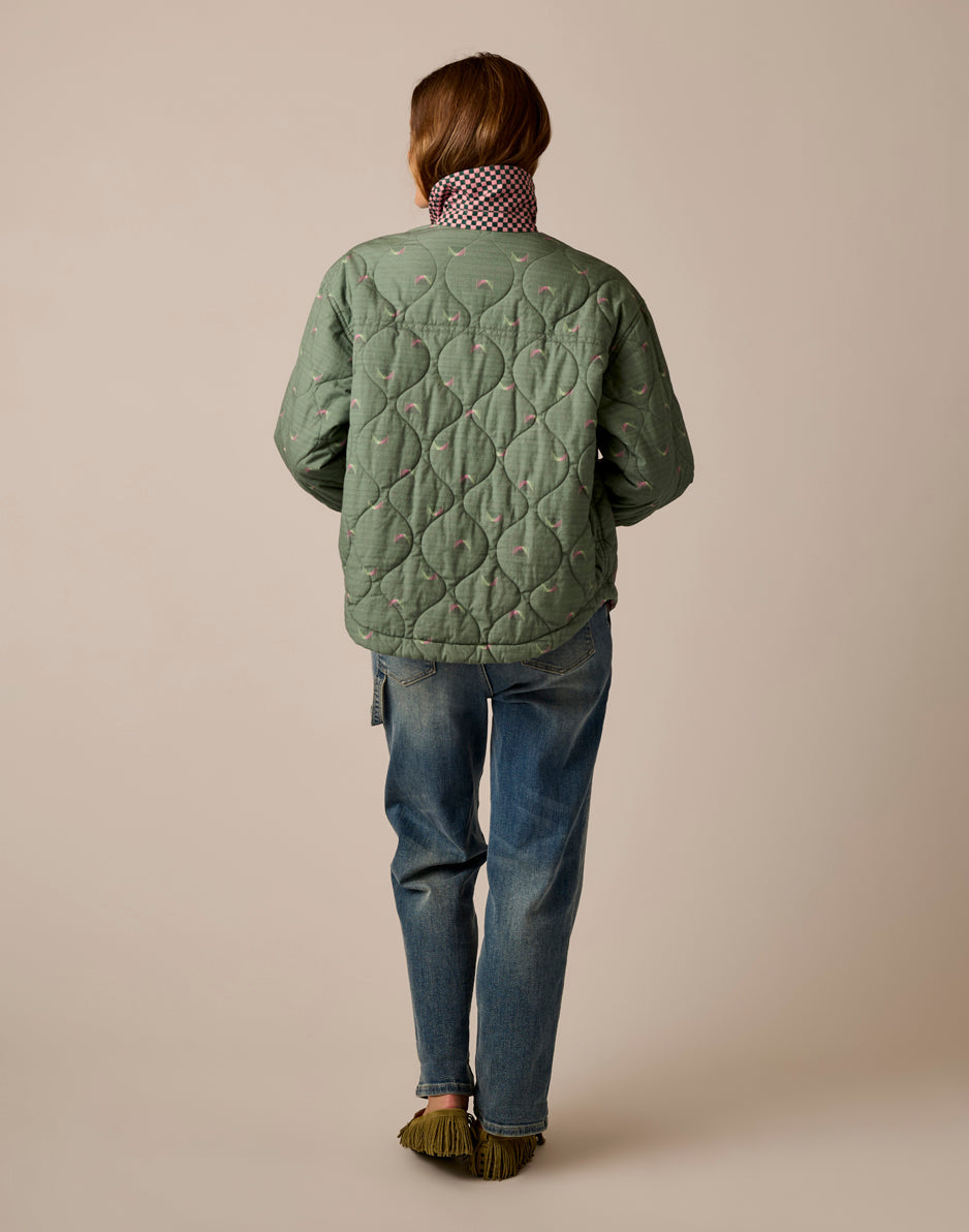 Back view of quilted reversible jacket in sage green with small print, paired with jeans
