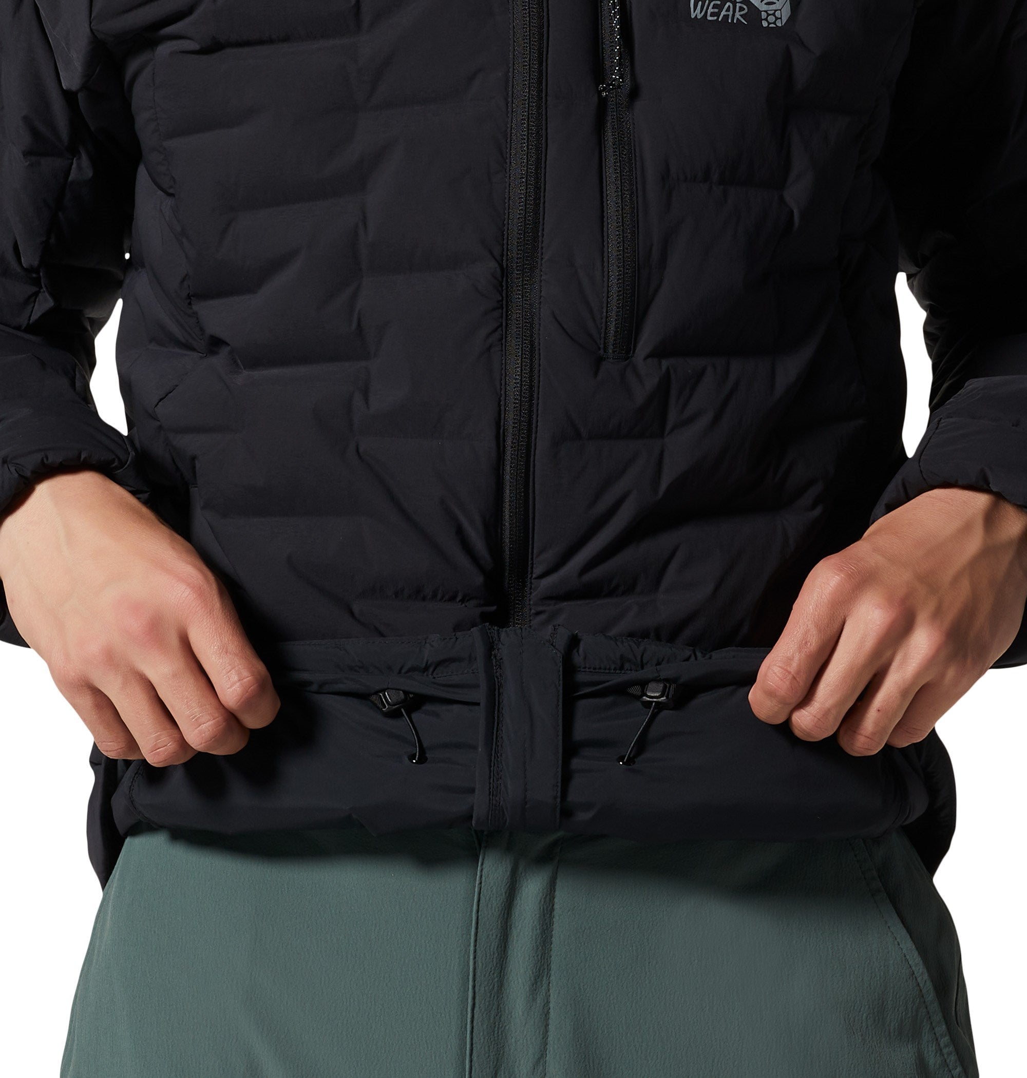 Close-up detail of black quilted down jacket showing hem adjustment cord and zip, on model