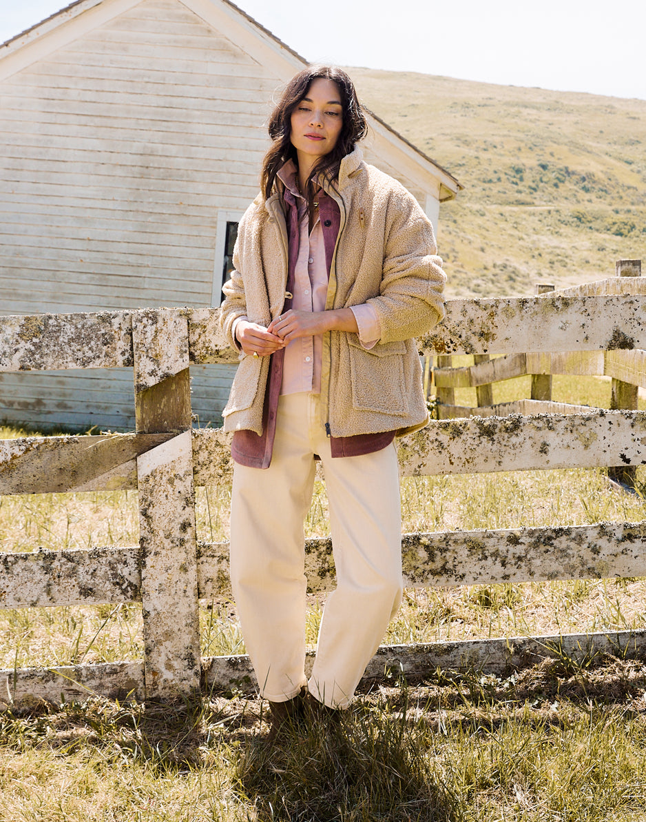 Women's oversized cream boucle coat worn open over layered shirt and wide-leg pants, outdoor setting