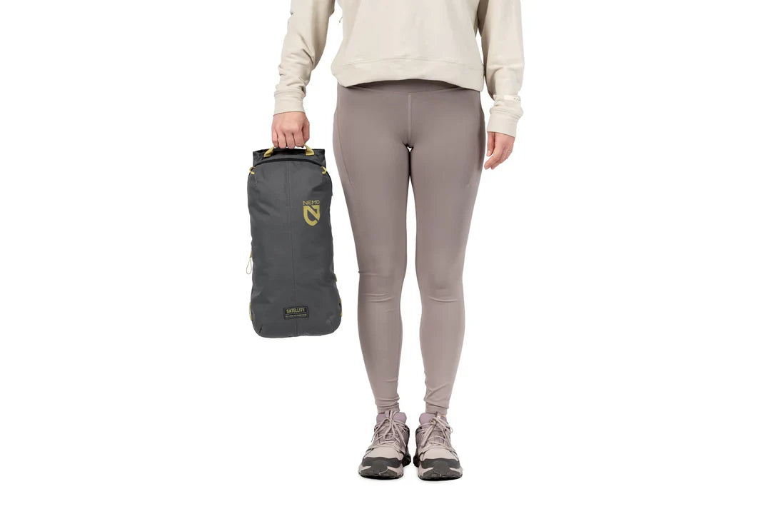Person holding a compact packed grey camping chair bag with yellow logo, side view
