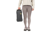 Person holding a compact packed grey camping chair bag with yellow logo, side view