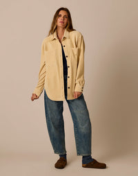 Oversized cream button-up shacket with chest pockets, worn open over navy top with wide-leg jeans