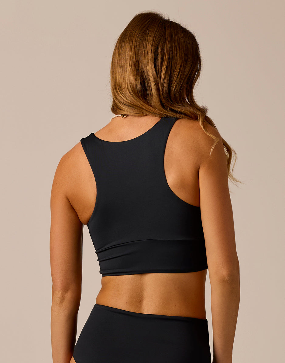 Women's black sleeveless crop top with racerback design, rear view on model