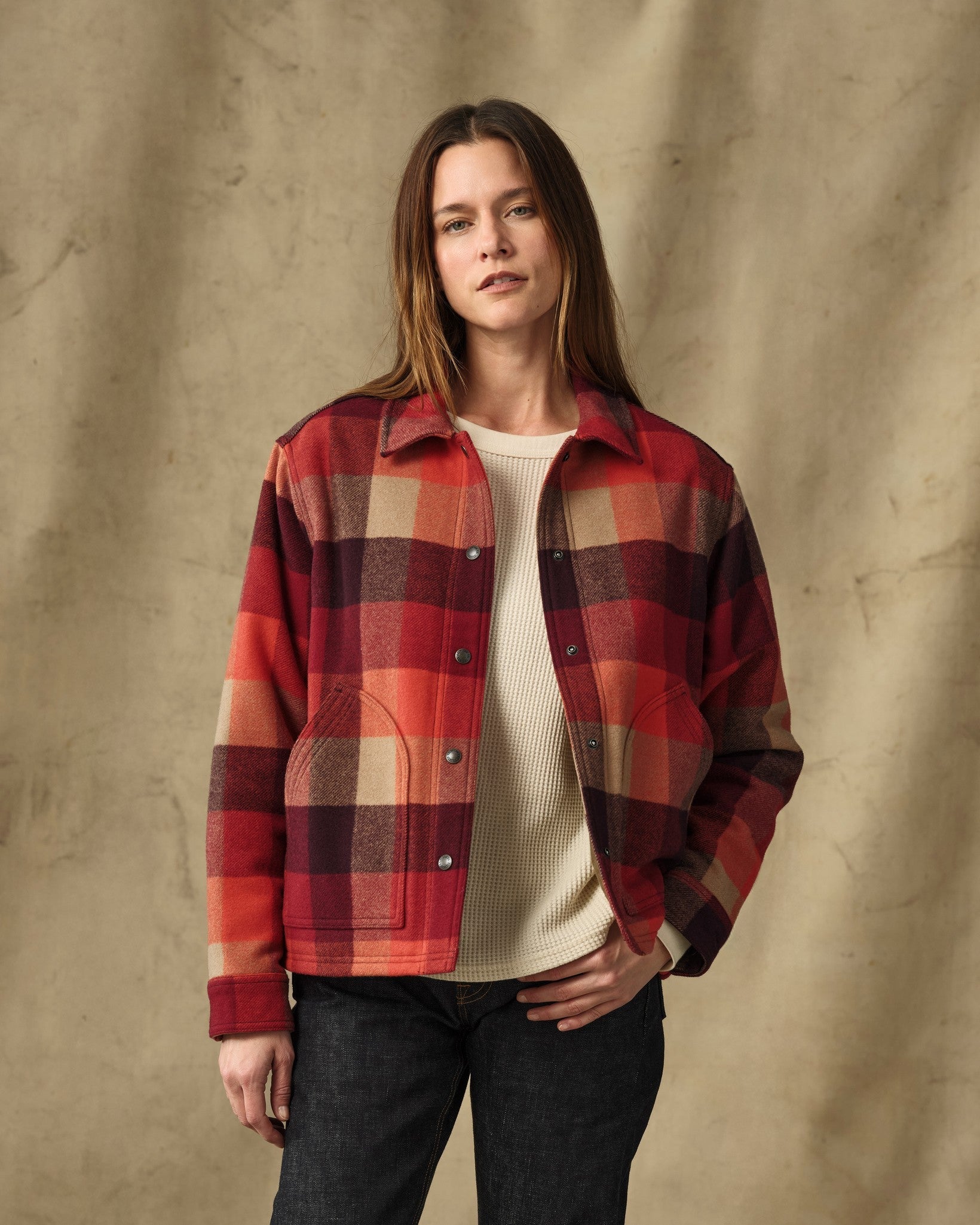 Women's plaid insulated jacket with snap buttons, worn open over cream sweater, front view