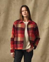 Women's plaid insulated jacket with snap buttons, worn open over cream sweater, front view
