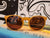 Round wooden sunglasses with amber lenses sitting on colorful surface with artistic background