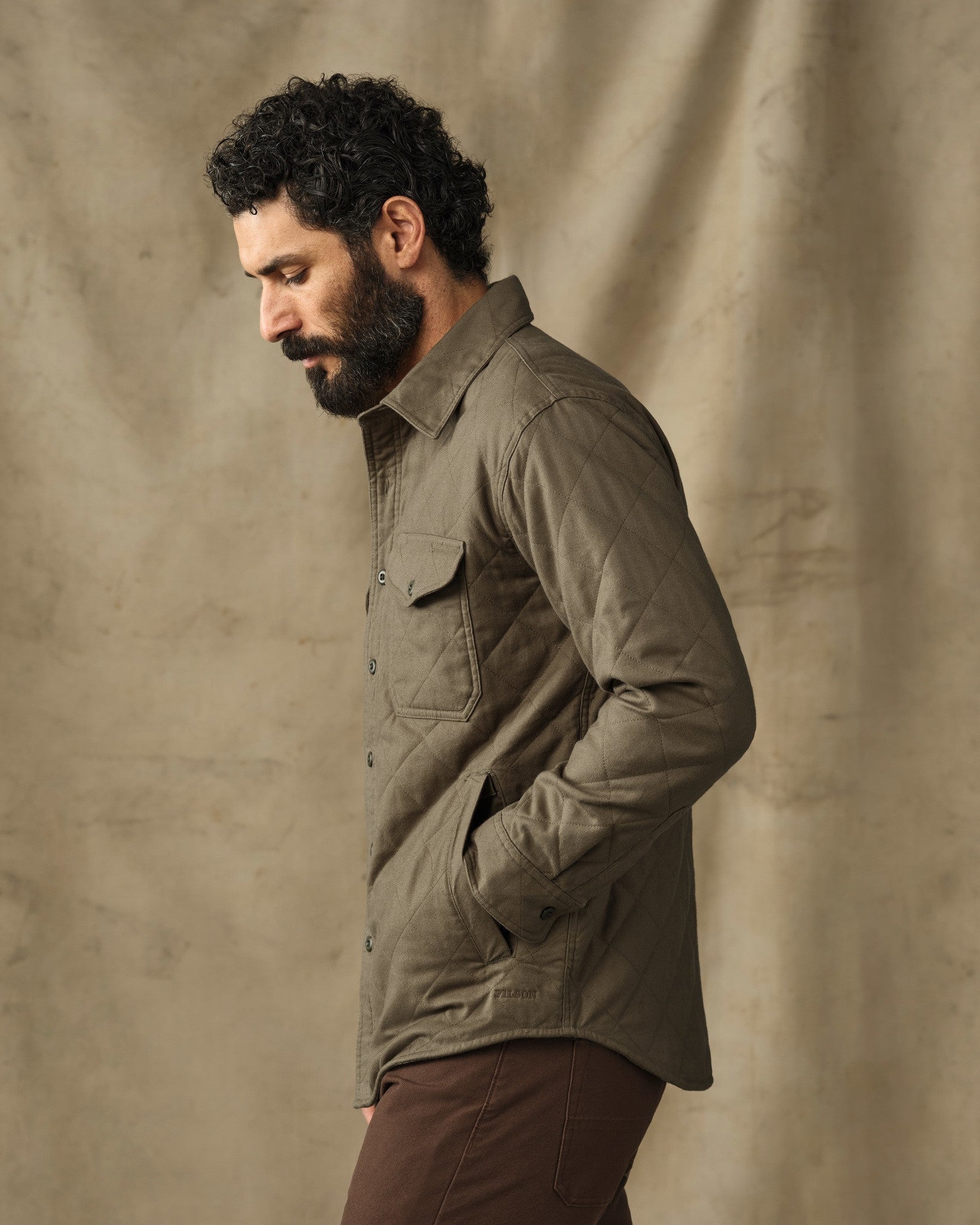 Men's quilted insulated shirt jacket in olive green with chest pockets, side profile view