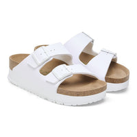 White two-strap slide sandals with buckles and cork footbed on clean background