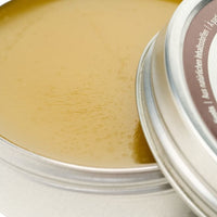 Open round container showing translucent yellow leather conditioning balm with smooth waxy texture