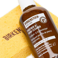 Shoe cleaner bottle with brown liquid and cleaning cloth on yellow background