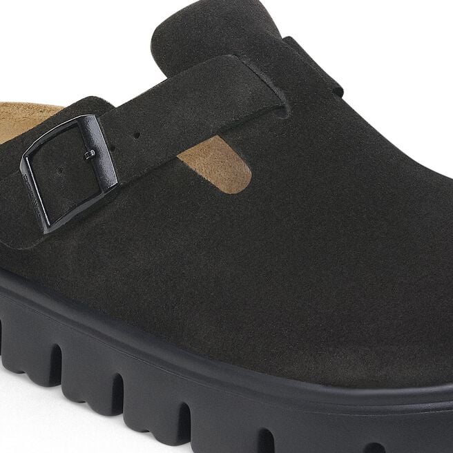 Close-up detail of black suede clog with buckle strap and chunky lug sole