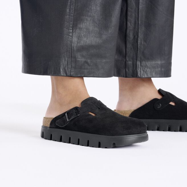 Black suede closed-toe clogs with buckle strap and chunky lug sole, on-model view