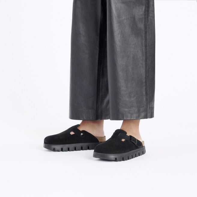 Black suede closed-toe clogs with chunky sole and buckle strap, on-model view