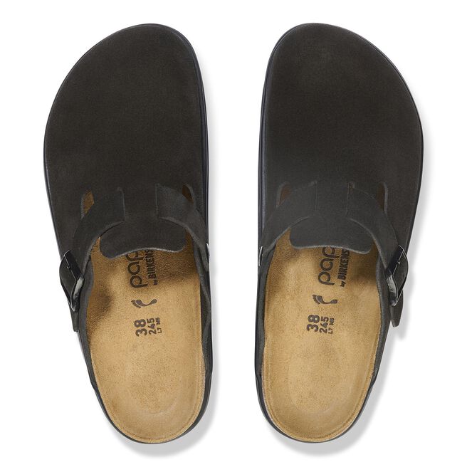 Top-down view of a pair of black suede closed-toe clogs with buckle strap and cork footbed