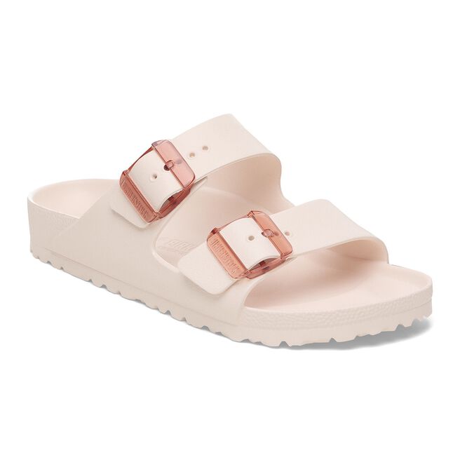 Two-strap slip-on sandals in light pink with rose gold buckles on white background