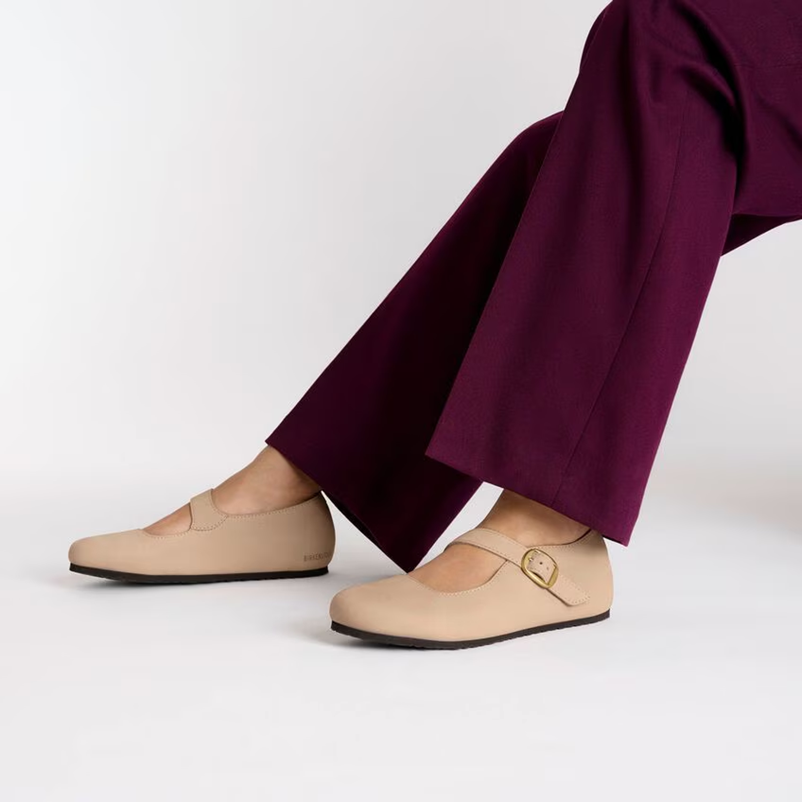 Light beige closed-toe clogs with buckle strap worn with purple wide-leg pants