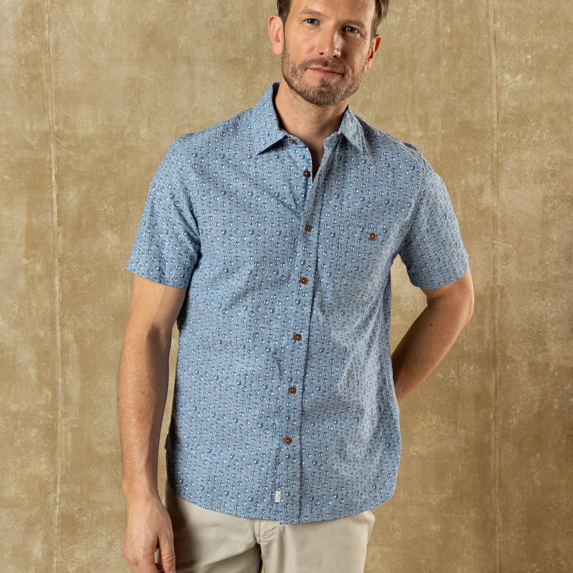Light blue short-sleeve button-up shirt with small print pattern, front view on model
