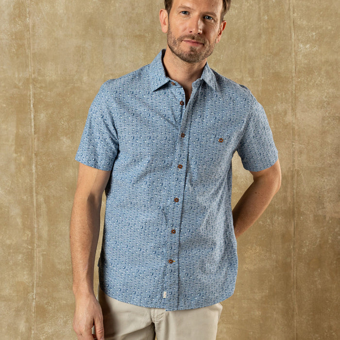 Light blue short-sleeve button-up shirt with small print pattern, front view on model
