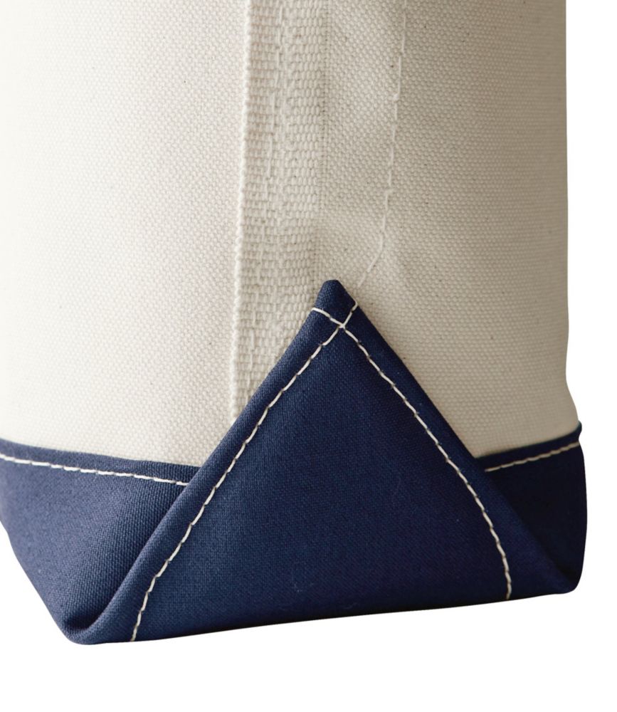 Close-up of canvas tote bag corner showing natural fabric with navy blue reinforced base