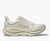 Light colored running shoe with mesh upper and thick cushioned sole, side profile view