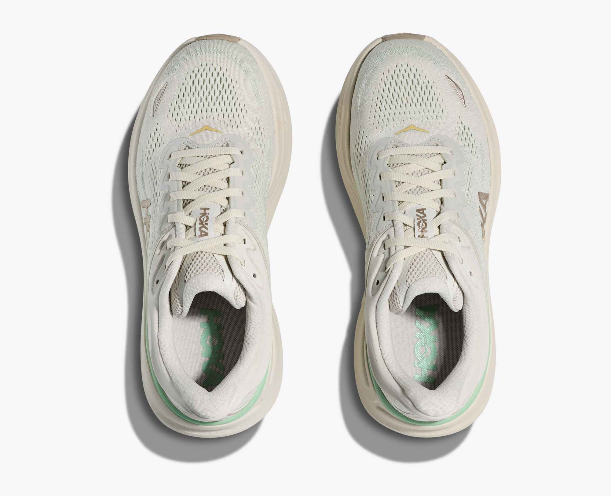 Light colored running shoes with mesh upper, top-down view showing laced design and breathable construction