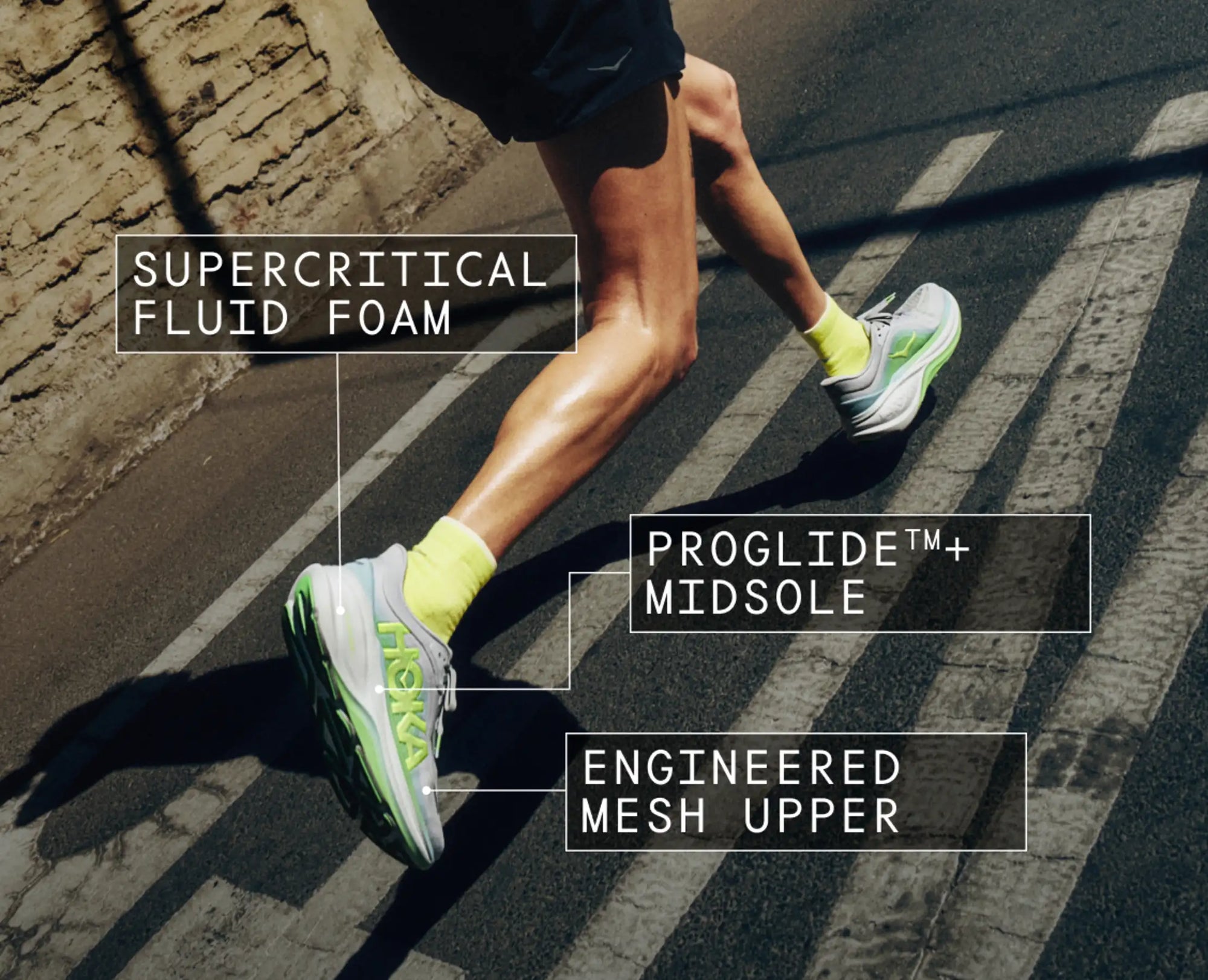 Runner wearing cushioned running shoes with neon green accents, mid-stride on crosswalk, featuring labeled technology callouts