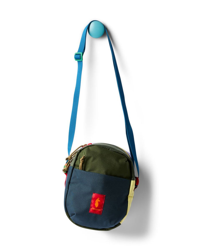 Round crossbody shoulder bag in colorblock navy and olive, hanging on a wall hook