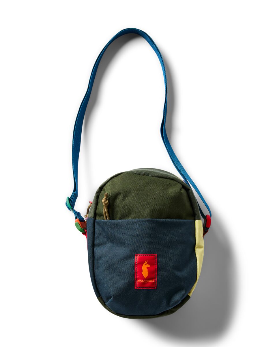 Small round crossbody shoulder bag with multicolor patchwork panels, zippered front pocket, blue strap