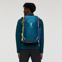 Blue travel backpack with colorful rainbow straps worn by person, rear view