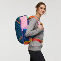 Colorful patchwork travel backpack worn by woman, showing vibrant multi-colored panels and straps