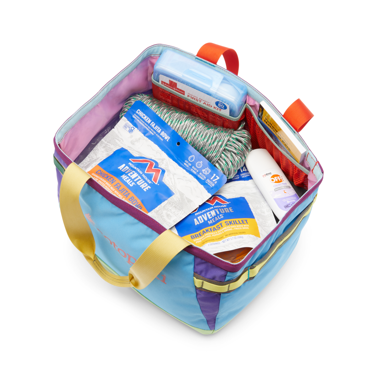 Colorful patchwork tote bag open showing packed outdoor gear and food items inside