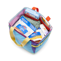 Colorful patchwork tote bag open showing packed outdoor gear and food items inside