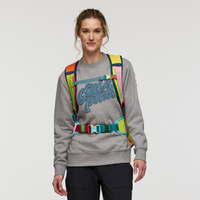 Multicolored travel backpack with rainbow panels worn by woman in gray sweatshirt