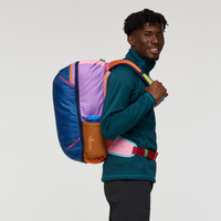Multicolored travel backpack with colorful panel design worn by person against white background