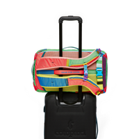 Multicolored travel backpack with colorful patchwork panels on rolling suitcase handle