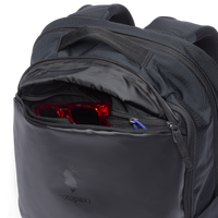 Black travel daypack with open main compartment showing red packing cubes and organizational features