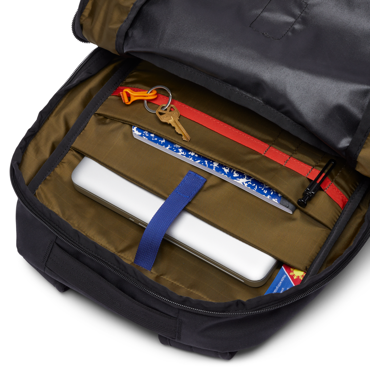 Interior view of a 26L backpack showing organized compartments with laptop sleeve, keys, notebook, and accessories