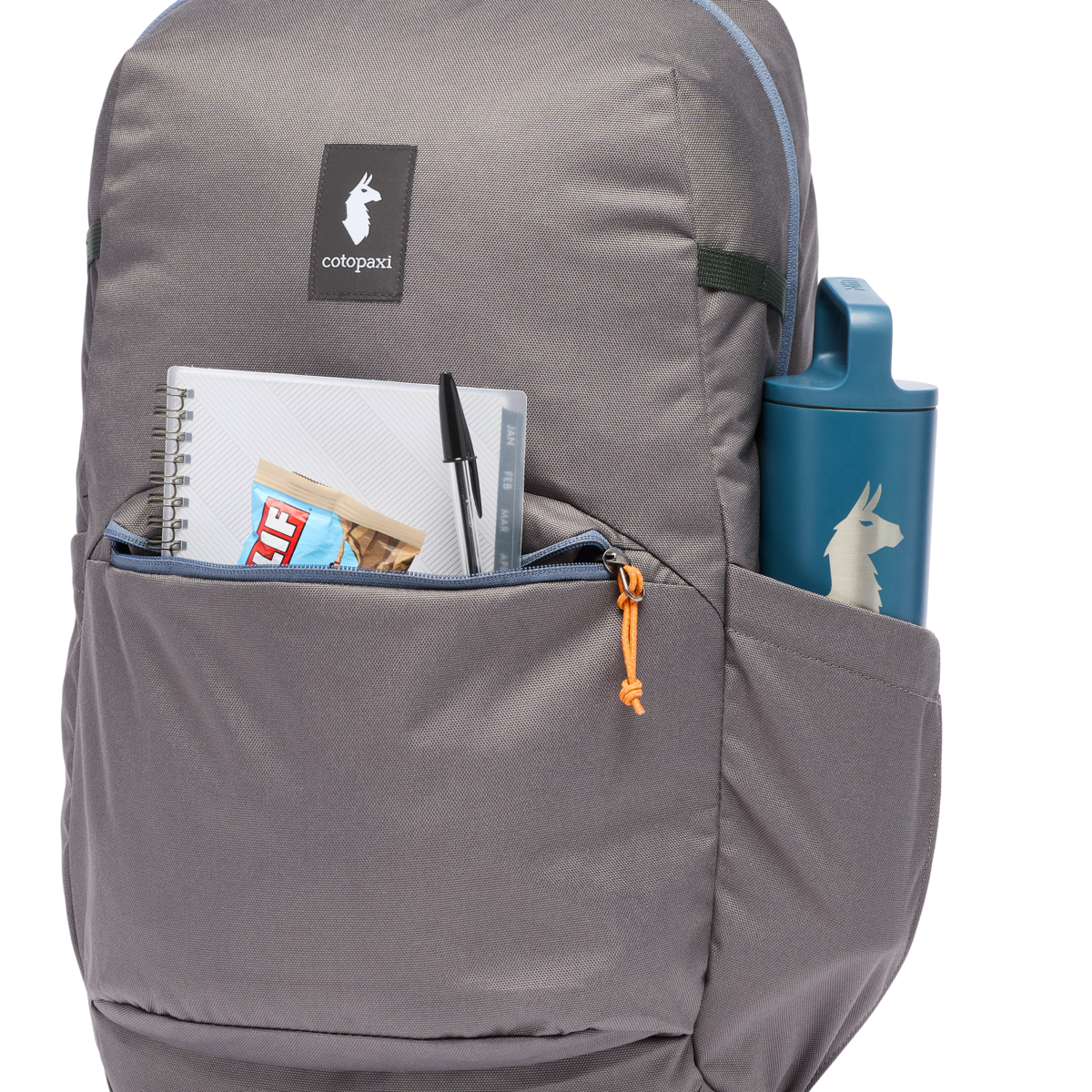 Gray backpack detail shot showing front pocket with notebook, pen, snack bar, and side water bottle pocket