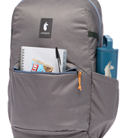 Gray backpack detail shot showing front pocket with notebook, pen, snack bar, and side water bottle pocket